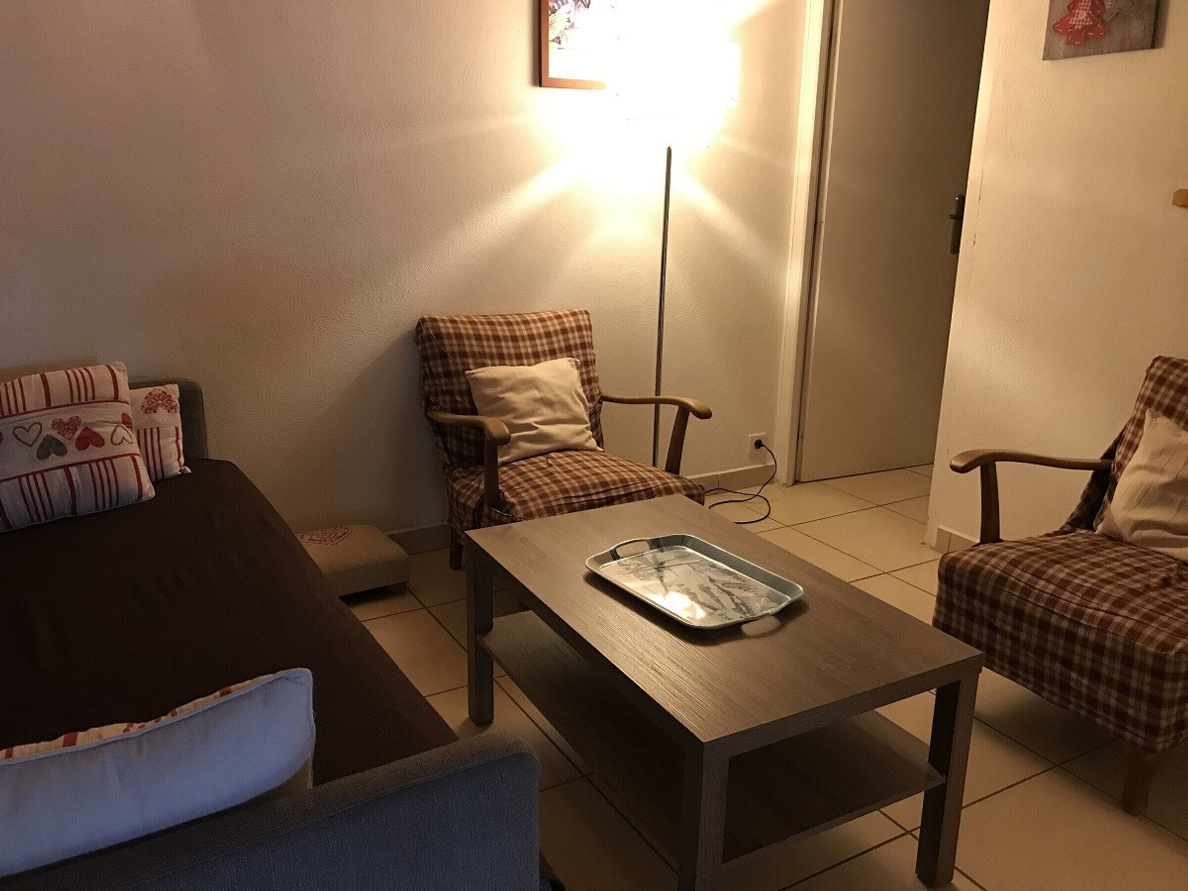 Ein Wohnzimmer mit einem braunen Sofa, einem blauen Sessel, einem Holztisch und zwei karierten Sesseln.