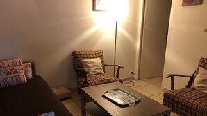 A living room with a brown sofa, a blue armchair, a wooden coffee table, and two plaid chairs. - Apartment with parking, pets welcome - 8 guests (Arâches-la-Frasse)