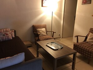 A living room with a brown sofa, a blue armchair, a wooden coffee table, and two plaid chairs. - Apartment with parking, pets welcome - 8 guests (Arâches-la-Frasse)