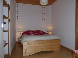 Ein Schlafzimmer mit einem hölzernen Bett, zwei Nachttischlampen, einer Hockerleiter und einer Stern-Dekoration, die von der Decke hängt.