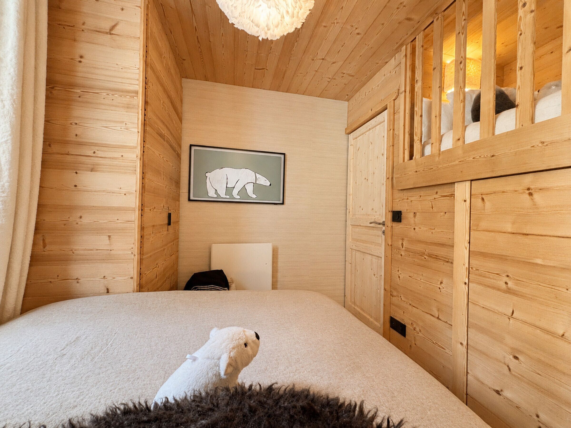 Una habitación acogedora de madera con una cama, un cuadro de un oso polar enmarco y una alfombra mullida.