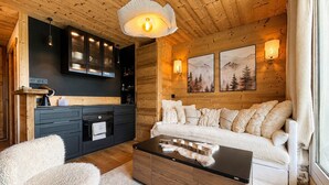 L’intérieur d’un chalet confortable, avec un canapé, une table basse et un coin cuisine.