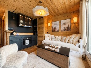 Ein gemütliches Blockhaus-Interieur mit einer Couch, einem Couchtisch und einer Küchenzeile.