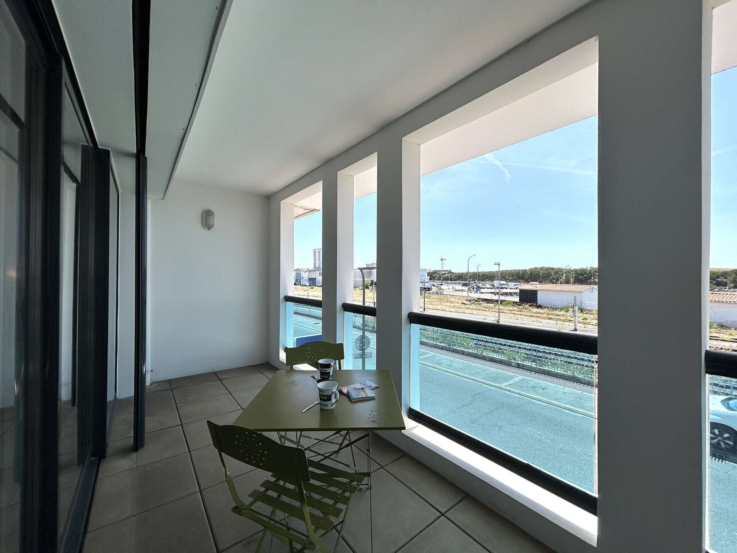 Un balcone con tavolo, sedie e vista su un'area di parcheggio.