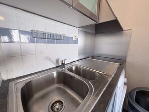 A kitchen with two stainless steel sinks, a tiled backsplash, and a stainless steel range hood. - Apartment in Gruissan, ideal location (Gruissan)