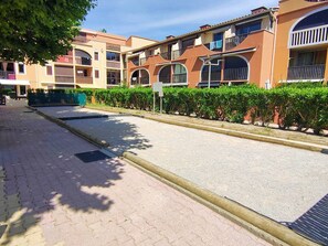 A residential building with multiple balconies, a paved street, and a hedge along the sidewalk. - Studio with pool and parking - 4 guests (Canet-en-Roussillon)