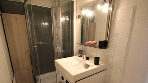 A compact bathroom with a glass-enclosed shower, a sink with a mirror, and a toilet. - Apartment with mountain view - 4 guests (Bagnères-de-Luchon)