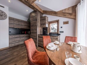 Uma cozinha moderna com armários de madeira, forno embutido e área de jantar com mesa e cadeiras de madeira.