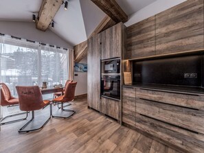 Eine moderne Küche mit Holzausstattung, einem eingebauten Ofen und einem Essbereich mit Stühlen.