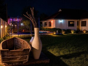 Ein Haus mit Swimmingpool, einem Holzboot und einer großen Pflanzvase.