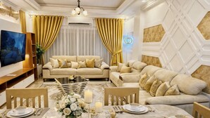 A well-appointed living room with a sofa set, a dining table set for four, and a flat-screen TV.