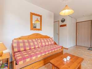 Ein Zimmer mit einer Holzcouch, einem Holztisch mit Tassen, einer Lampe und einem Spiegel an der Wand.