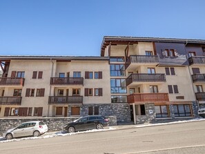 Un hôtel à plusieurs étages doté de balcons, d’une façade en pierre et d’un espace de stationnement.