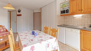 Ett kompakt kök med träskåp, en mikrovågsugn och en diskmaskin.
