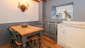 Un comedor con una mesa y sillas de madera, una escultura de cuerno montada en la pared y un ventanal con vistas.