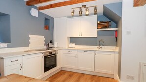Una cocina moderna con armarios blancos, una mesa de madera y un horno empotrado.