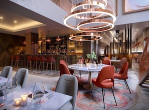 Un restaurant moderne avec des tables rondes, des chaises rouges et un bar situé au fond de la salle.