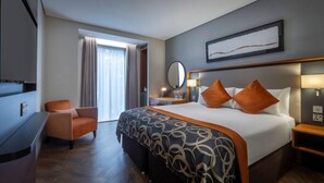 A hotel room with a large bed, a chair, a desk, and a window with curtains. - Clayton Hotel St Andrew Square, Edinburgh (Edinburgh)