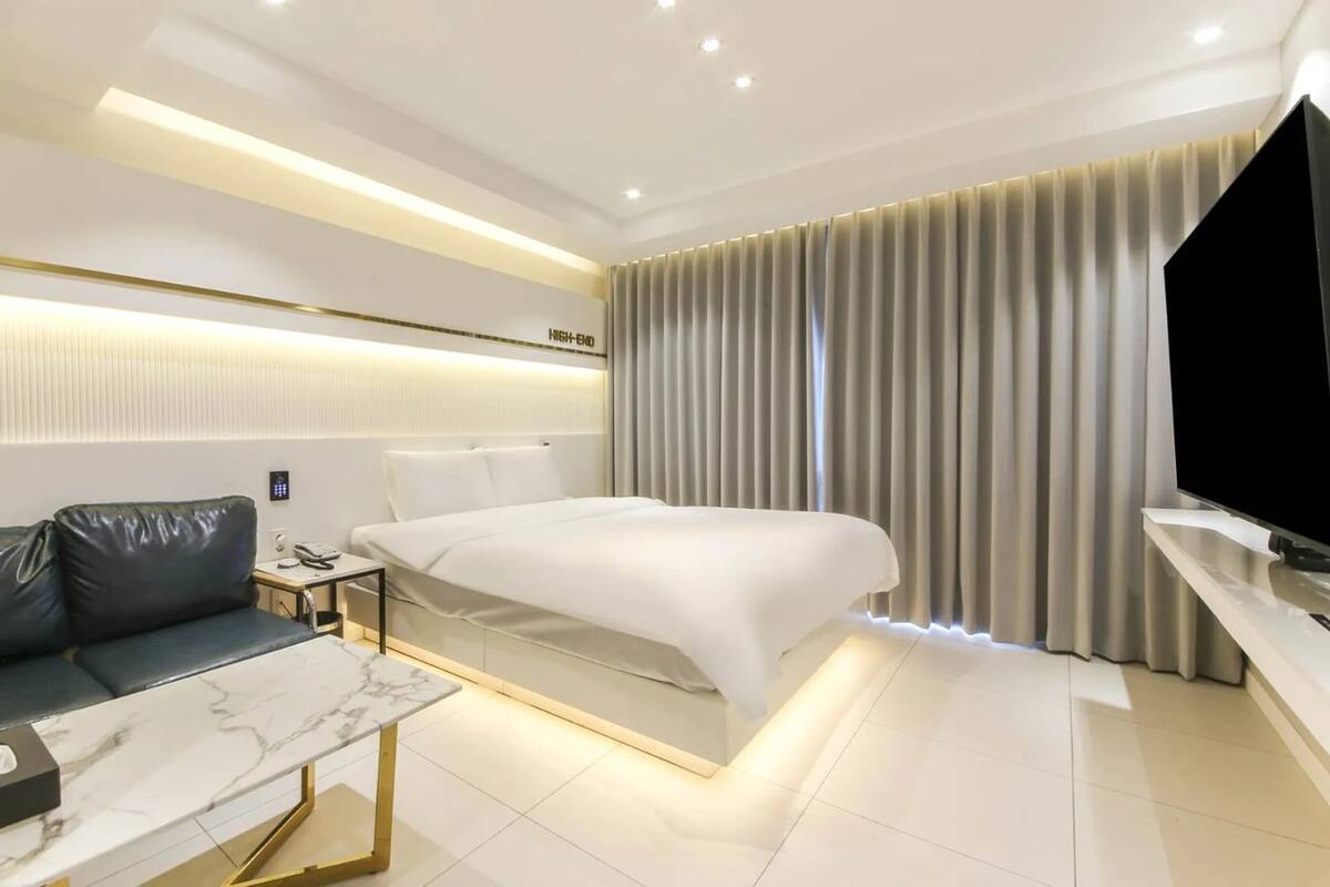 Ein modernes Hotelzimmer mit Bett, einer Couch, einem Fernseher und einem Nachttisch.