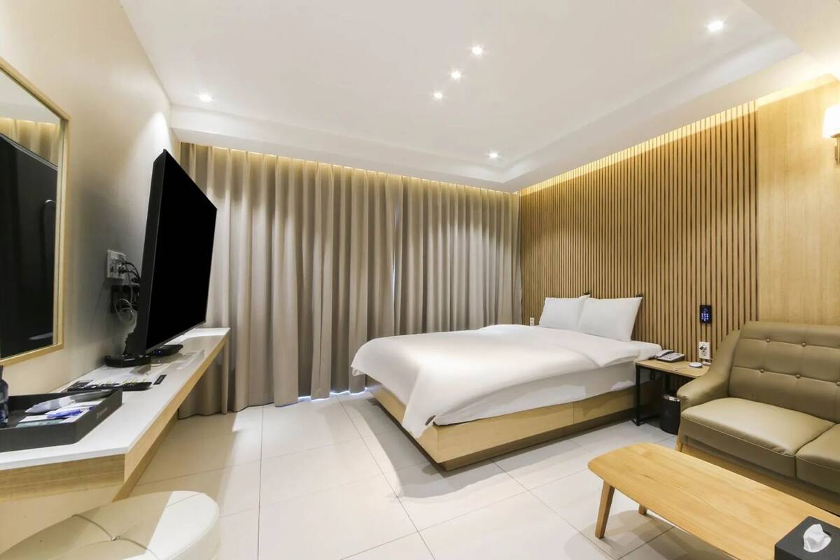 Ein Hotelzimmer mit Bett, Sofa, Schreibtisch mit Computer und Fernseher.