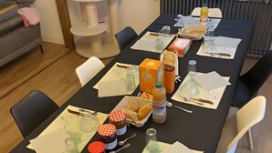Une table à manger dressée avec différents plats, des couverts et, en arrière-plan, un arbre à chat.