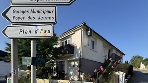 A building with a sign indicating 'Centre Sportif Départemental' and 'Garages Municipaux Foyer des Jeunes.' - Bed and Breakfast 'Chambre Félix' (Bugeat)
