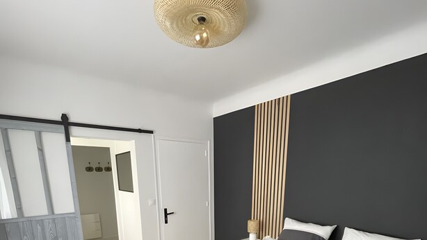 A modern bedroom with a large bed, a wooden floor, a dark headboard, and a ceiling light fixture. - Bed and Breakfast 'Chambre Félix' (Bugeat)