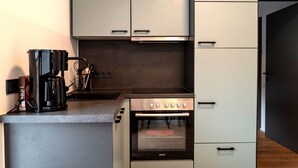 A compact kitchen with a built-in oven, a coffee maker, and a microwave.