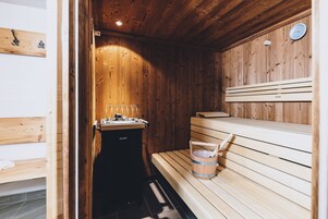 Una sauna de madera con bancos, calentador y un cubo.