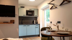 A compact kitchen with a microwave, coffee maker, and a dining area with a table set for two.
