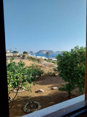 A view of a coastal landscape with buildings, a clear sky, and vegetation.