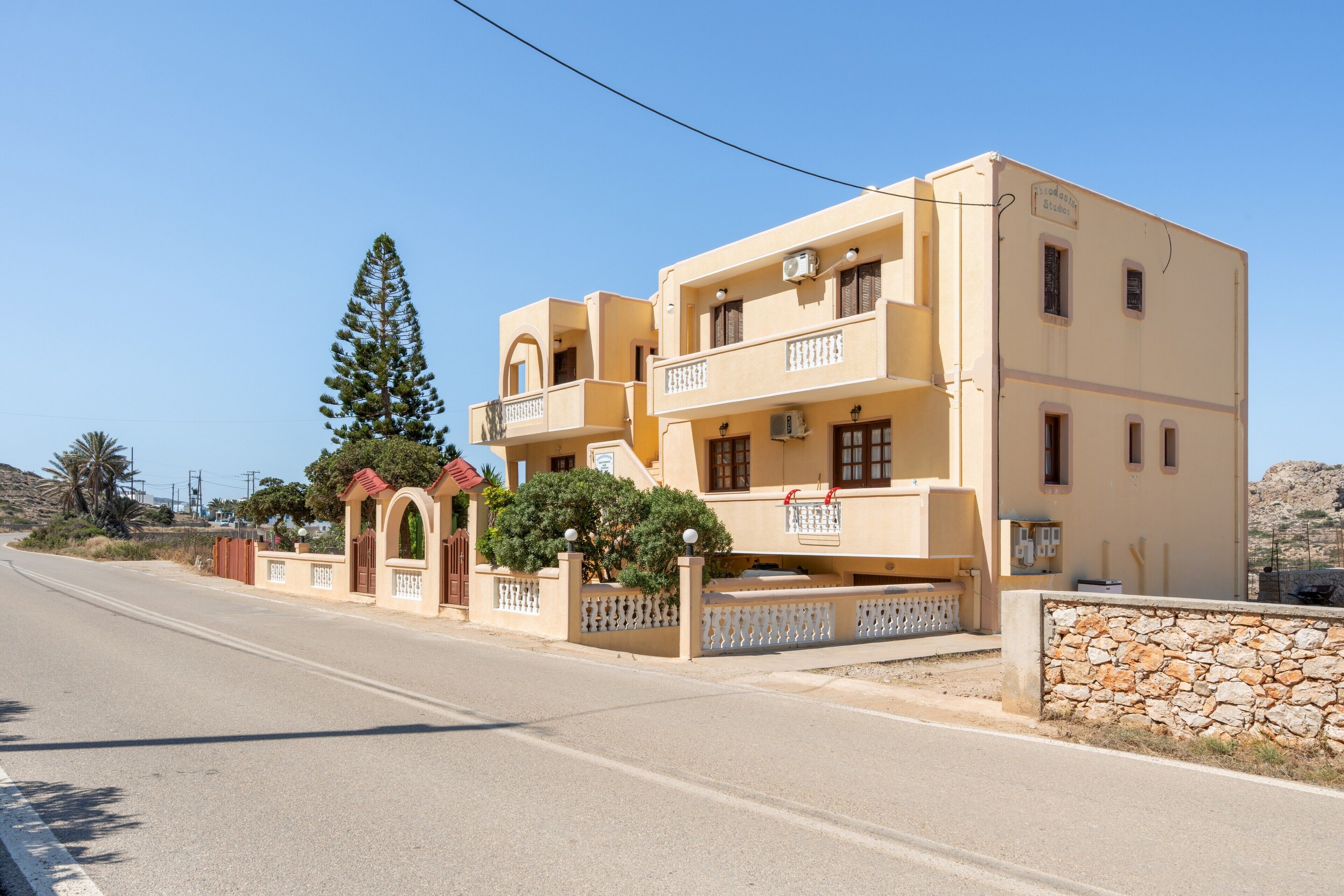 Un edificio di due piani con un balcone, un muro in pietra e cielo sereno.