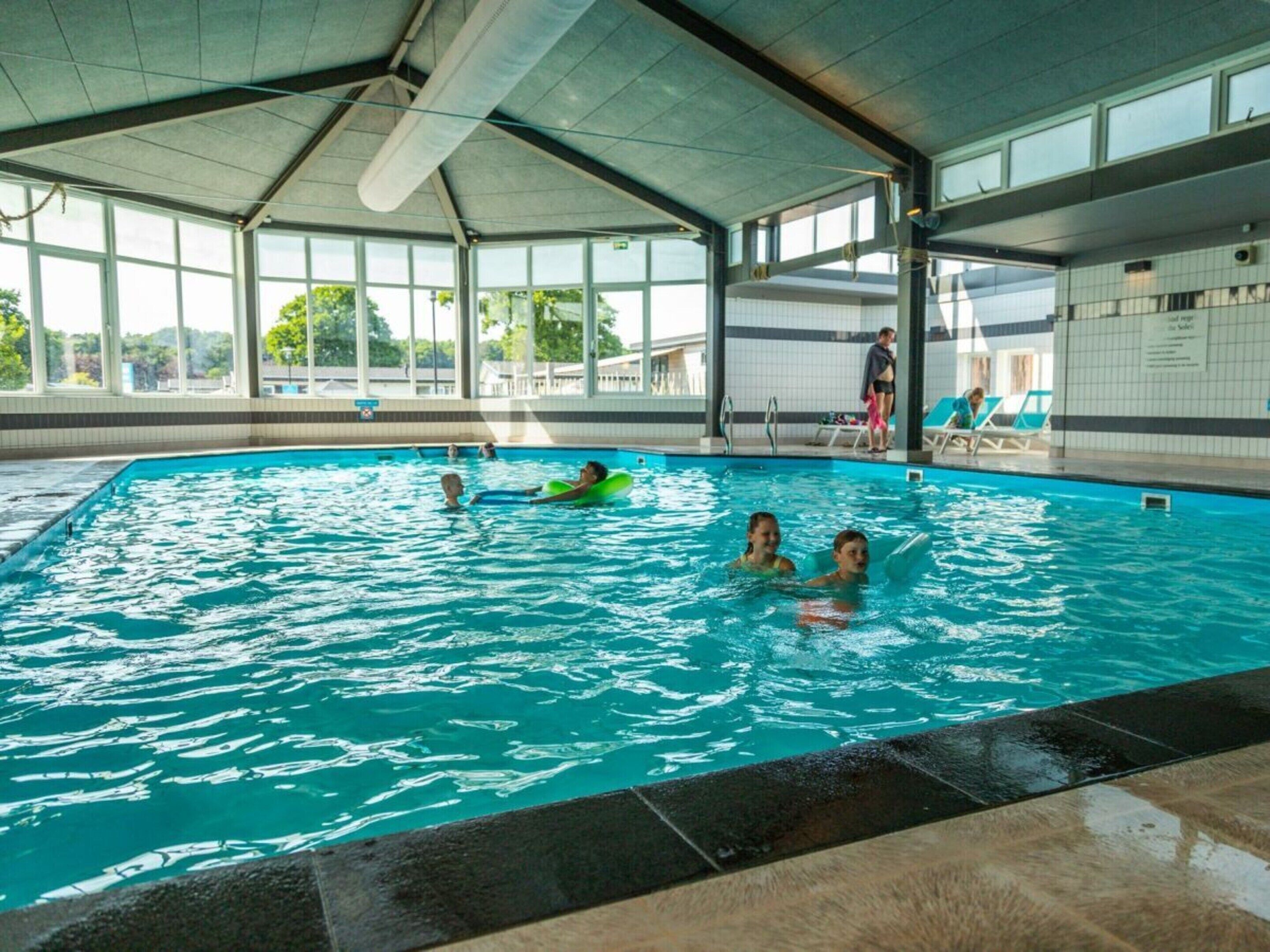Ein überdachter Innenpool mit klarem Wasser und gefliestem Boden.