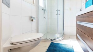 A modern bathroom with a toilet, a glass shower enclosure, and a wooden vanity. - Holiday Home in Noordwijk With Terrace (Noordwijk)