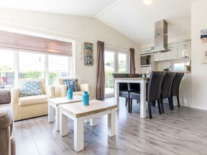 A modern living room with a sofa, a coffee table, and a dining area with chairs. - Holiday Home in Noordwijk With Terrace (Noordwijk)