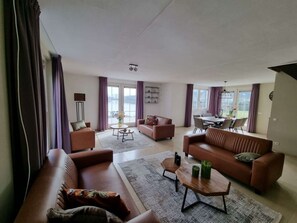 Ein geräumiger Wohnbereich mit einer Sofagarnitur, einem Couchtisch und einem Esstisch mit Stühlen.