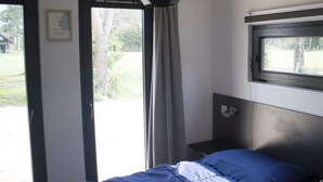 A bedroom with a bed, a window, a door, and a wall-mounted light fixture. - Holiday Home in Otterlo With Terrace (Otterlo)