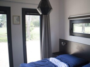 Ein Schlafzimmer mit Bett, Fenster, Tür und einer Wandleuchte.
