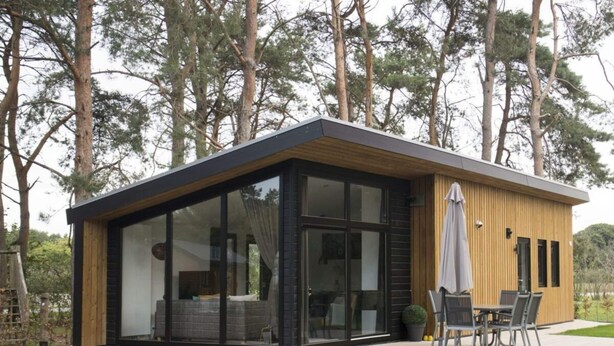 A modern house with large glass windows, a patio with outdoor furniture, and a wooden deck. - Holiday Home in Otterlo With Terrace (Otterlo)