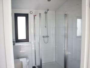 Ein Badezimmer mit Duschkabine, Toilette und Fenster.