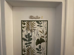 A framed botanical print with the text 'Chambre 3' on a white wall.