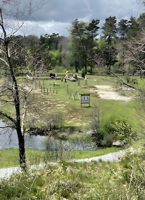 Ein Park mit Spielgeräten, einem kleinen Gebäude und einem Teich.