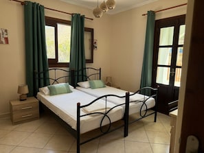 Une chambre avec deux lits, une table de chevet en bois, une commode, un miroir et une porte avec des rideaux.