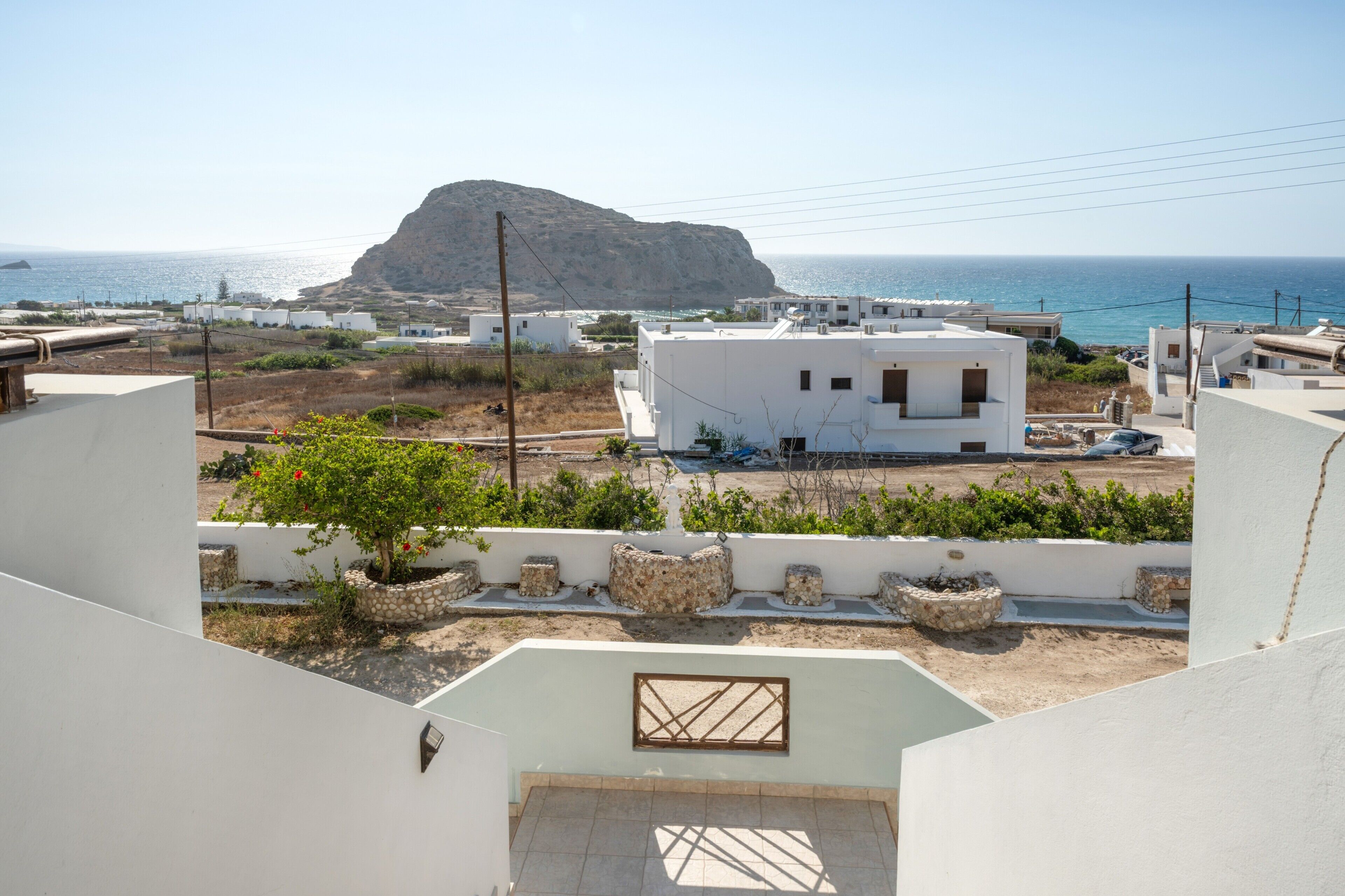 Un barrio residencial con edificios blancos, una colina rocosa y vista al mar.