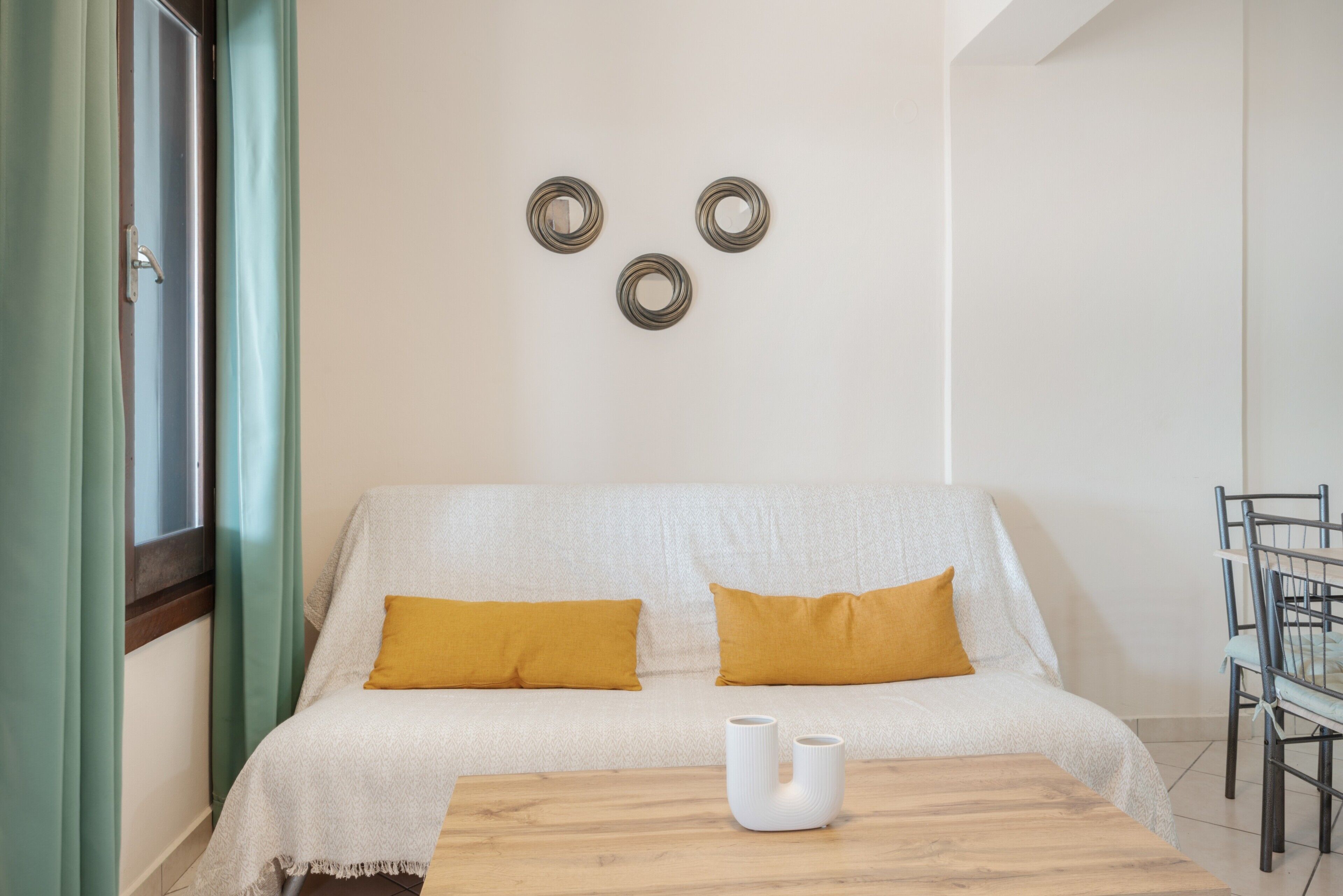 Ein Zimmer mit einem Bett, einem Tisch und einem Stuhl. Auf dem Bett liegen zwei Kissen.