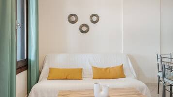 Ein Zimmer mit einem Bett, einem Tisch und einem Stuhl. Auf dem Bett liegen zwei Kissen.