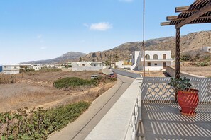 Ein Küstenwohngebiet mit weißen Gebäuden, einer gepflasterten Straße und einer Bergkulisse.