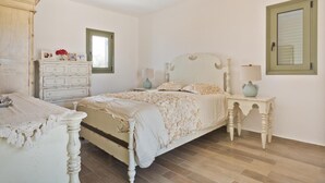 Quarto com cama, penteadeira, mesa de cabeceira e um lustre.