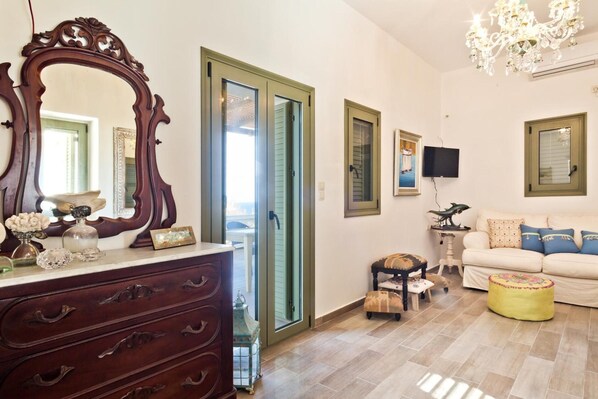 A living room with a large mirror, a sofa, a television, and a chandelier.