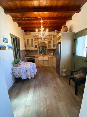A compact kitchen with wooden cabinets, a chandelier, and a dining table set with a floral tablecloth.